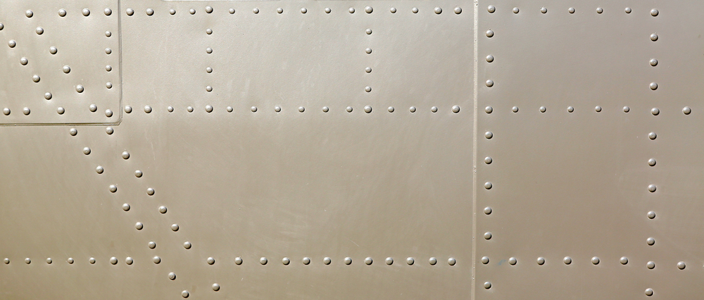 The metal surface of an airplane showing many rivets used as fasteners.