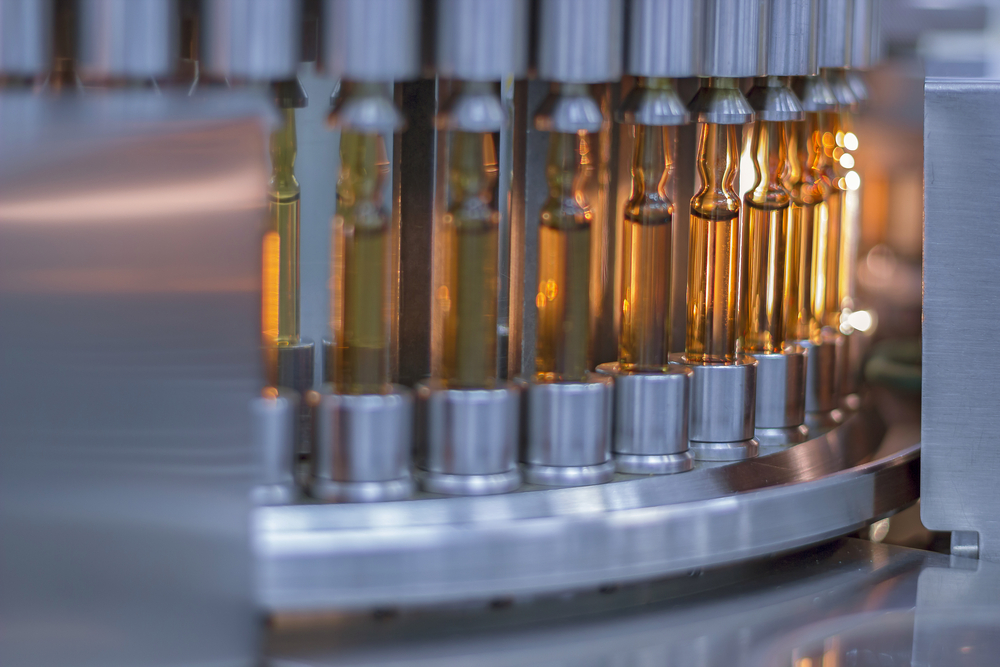 Glass vials containing liquid are handled by automated robotics equipment in a pharmaceutical application. 